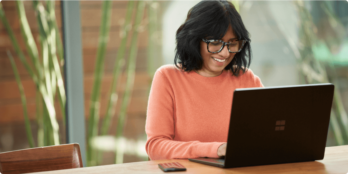 Une femme souriante travaillant dans un environnement de bureau ordinaire.